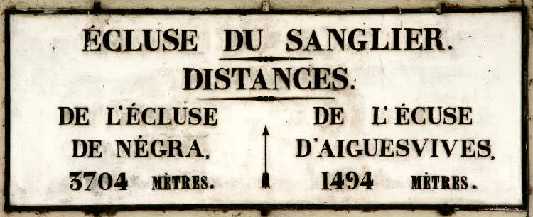 Plaque d'écluse informant l'usager de la voie d'eau du nom de celle-ci et de la distance qui le sépare des suivantes en amont et en aval. Celle-ci comporte une faute de frappe... L'aurez-vous remarqué?